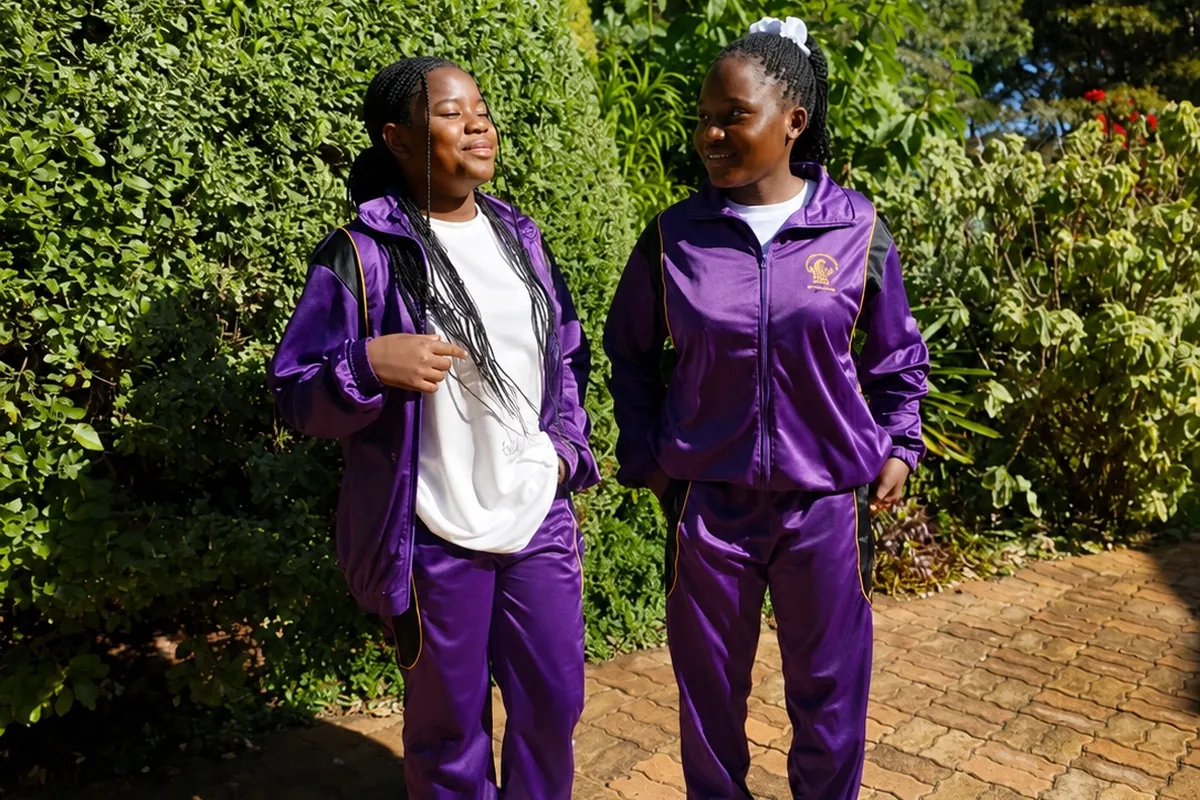 Two Privian Academy pupils in the school tracksuit in the school gardens