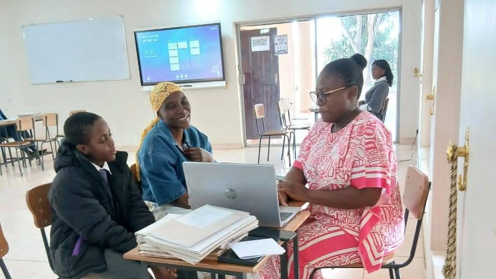 A parent and pupil going through paperwork with a member of Privian Academy staff at a laptop